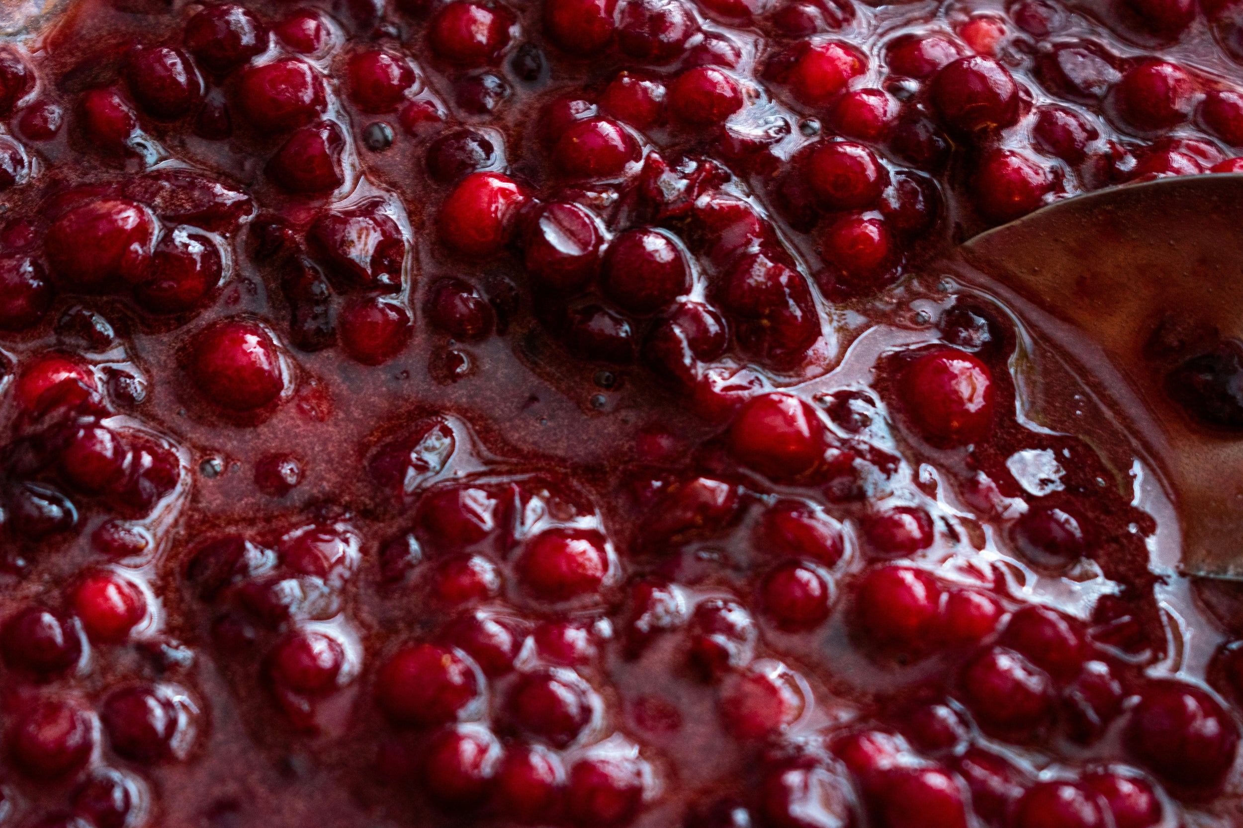 Gros plan de confiture de canneberges mijotée avec cuiller de bois