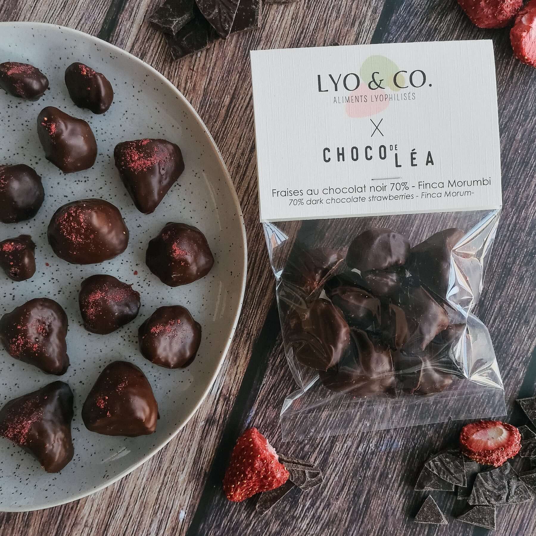 Fraises du Québec lyophilisées au chocolat noir 70% sur une assiette avec un sachet de produit.
