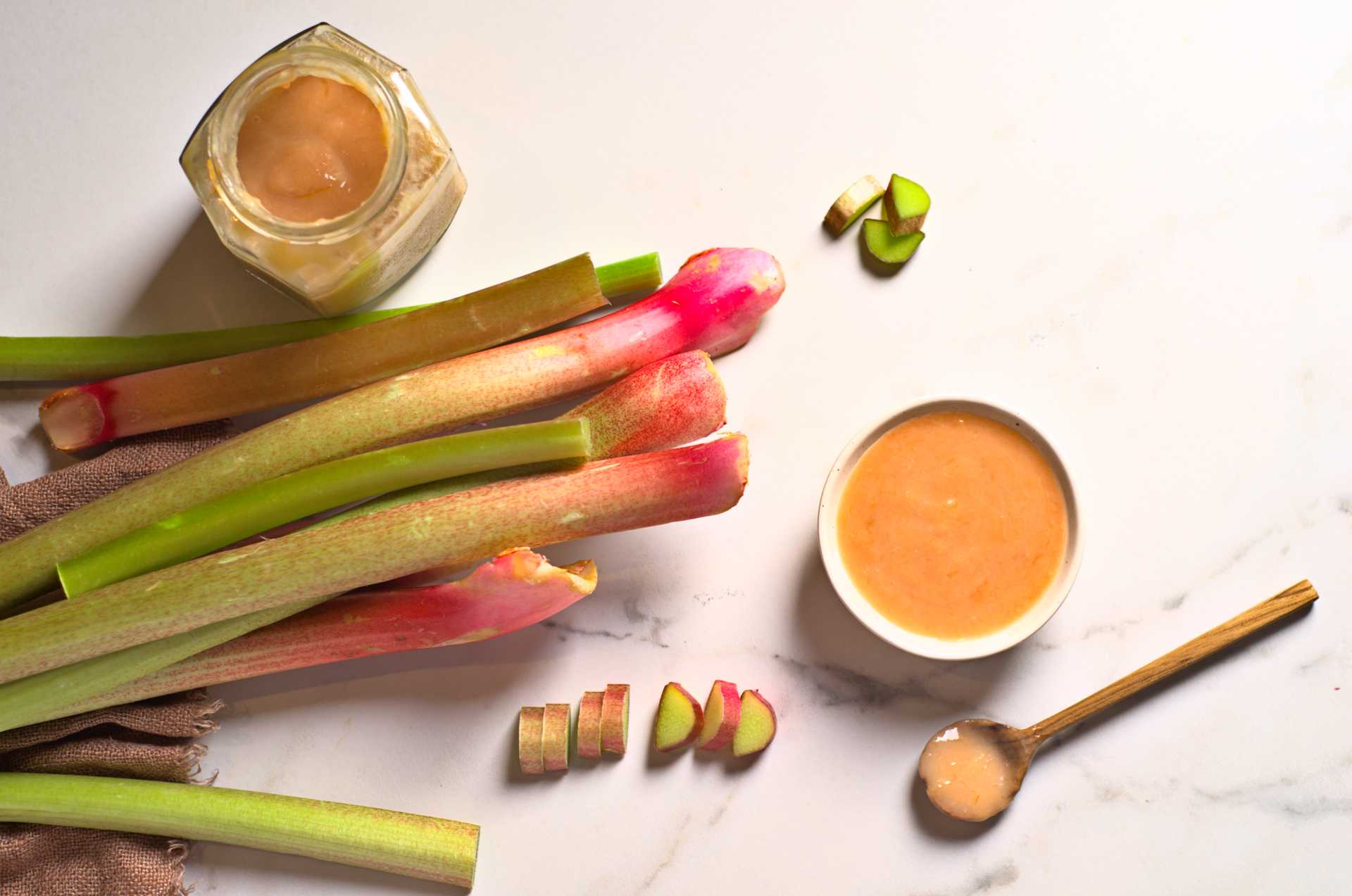 Rhubarbe fraîche en tiges avec compote de rhubarbe sur un comptoir en marbre blanc