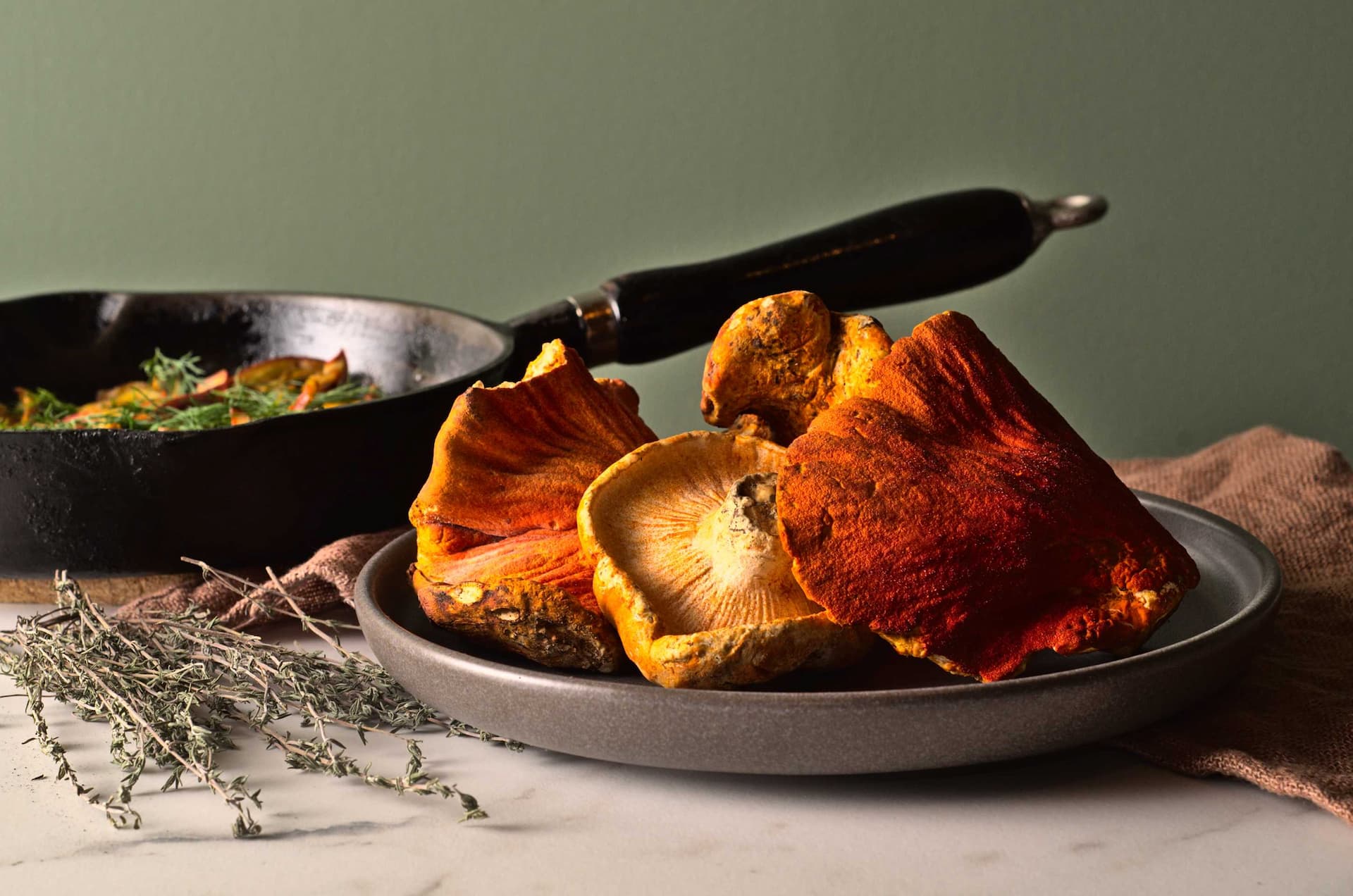 Champignons homards dans une assiette avec un poêlon en arrière-plan. Ces champignons sauvages sont aussi appelés champignons crabes ou champignons lobster.