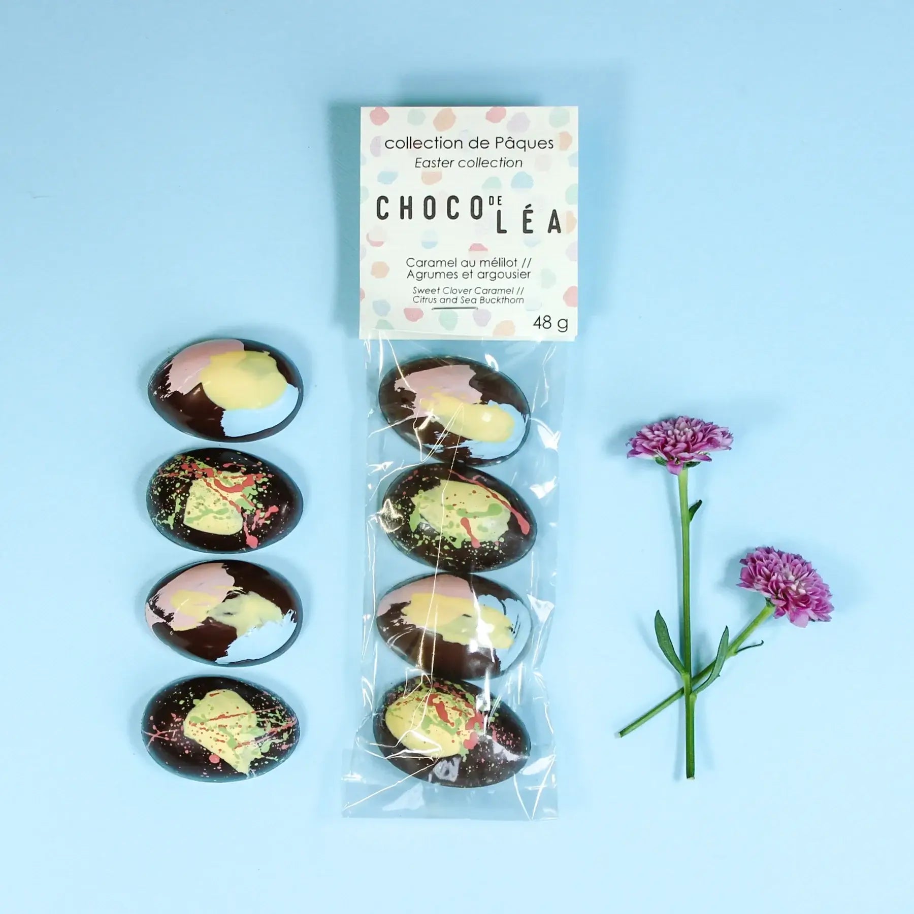 Demi-cocos de Pâques au caramel et agrumes, sachet de 48g, décor chocolaté artistique, avec fleurs décoratives.